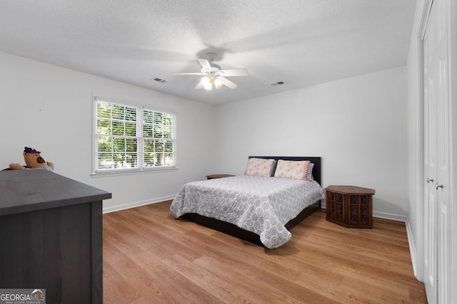 bedroom with ceiling fan, a closet, wood-type flooring, and a textured ceiling