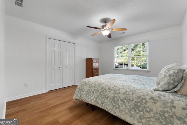 bedroom featuring a textured ceiling, a closet, ceiling fan, and wood-type flooring