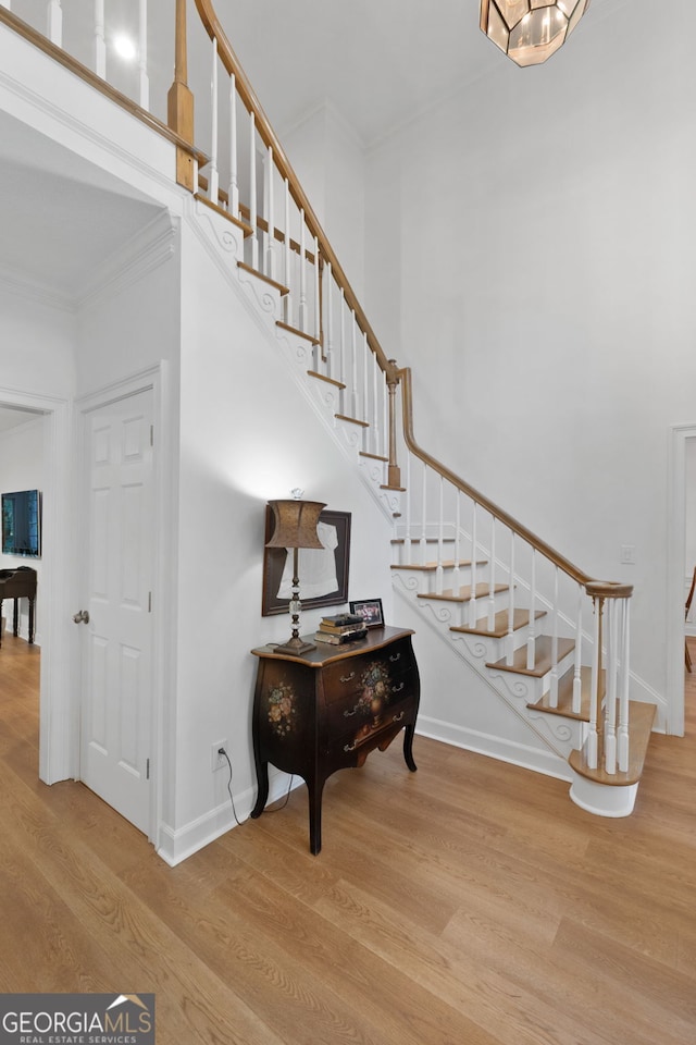 staircase featuring crown molding and wood-type flooring