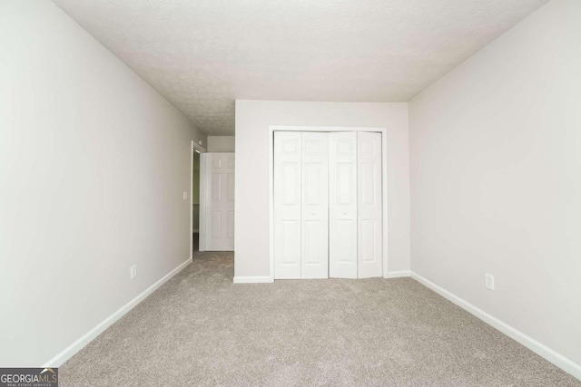 unfurnished bedroom with a textured ceiling, carpet flooring, and a closet