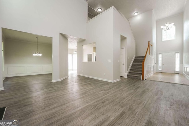 unfurnished living room with high vaulted ceiling, a chandelier, and dark hardwood / wood-style floors