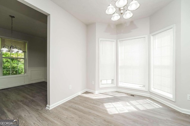 spare room featuring an inviting chandelier and hardwood / wood-style flooring