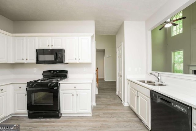 kitchen with sink, white cabinets, light hardwood / wood-style flooring, black appliances, and ceiling fan