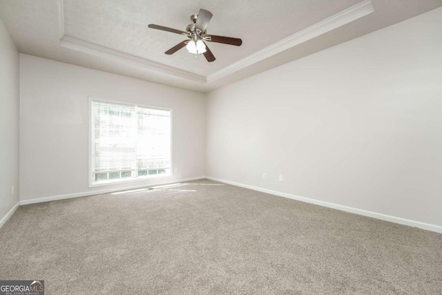 empty room featuring ceiling fan, a raised ceiling, crown molding, and carpet flooring