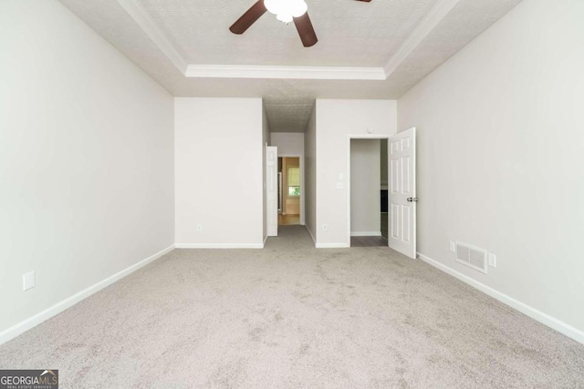 unfurnished bedroom with ceiling fan, a tray ceiling, a textured ceiling, and carpet flooring