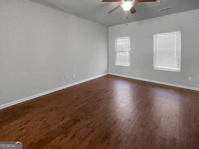 empty room with ceiling fan and dark hardwood / wood-style flooring