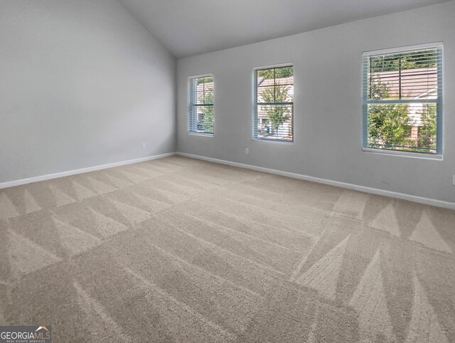 carpeted spare room featuring lofted ceiling and a healthy amount of sunlight