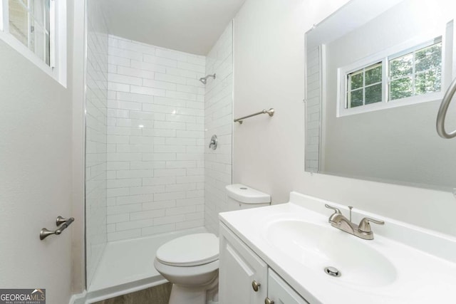 bathroom featuring tiled shower, vanity, and toilet