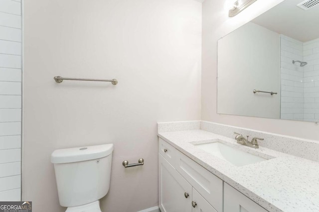 bathroom featuring a tile shower, vanity, and toilet