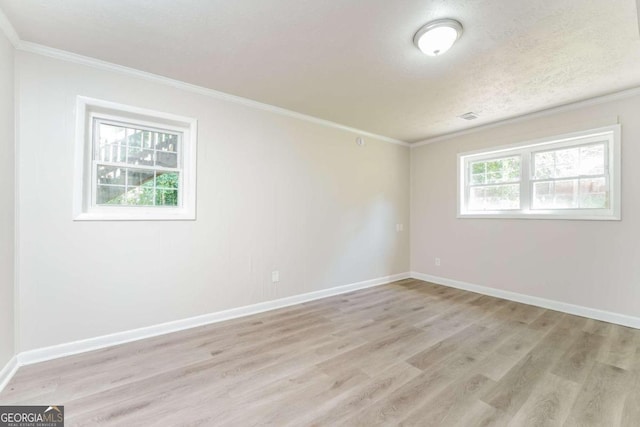 empty room with a textured ceiling, crown molding, and light hardwood / wood-style floors