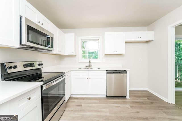 kitchen featuring stainless steel appliances, light hardwood / wood-style floors, a wealth of natural light, and sink