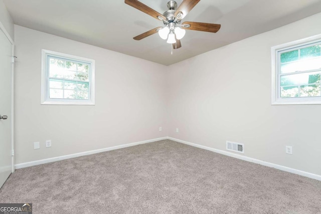 carpeted empty room with ceiling fan and plenty of natural light