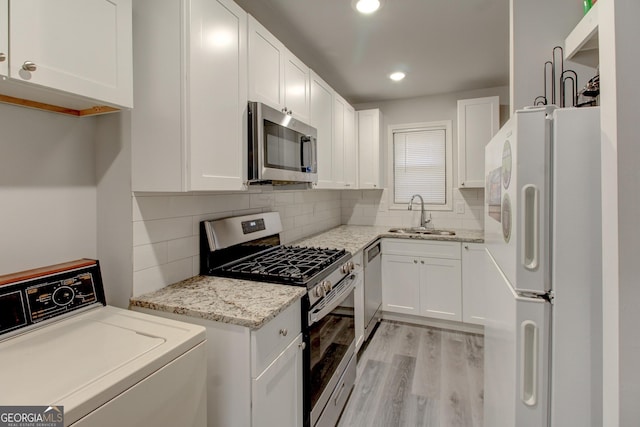 kitchen with sink, light hardwood / wood-style flooring, white cabinetry, stainless steel appliances, and washer / dryer