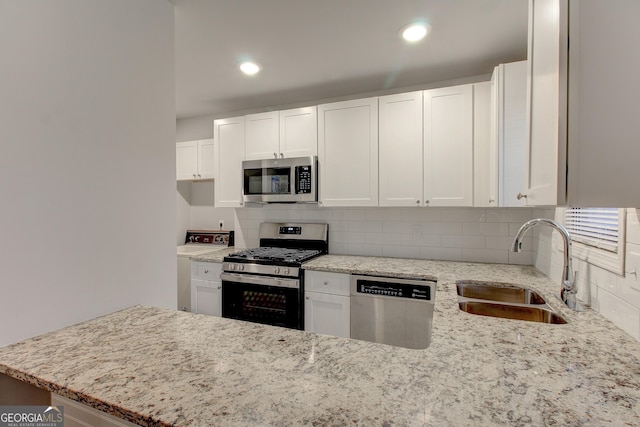 kitchen featuring sink, white cabinetry, appliances with stainless steel finishes, light stone countertops, and decorative backsplash