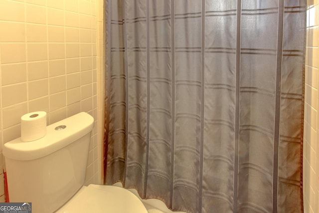 bathroom featuring tile walls and toilet