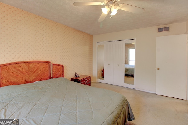 carpeted bedroom featuring ceiling fan, a textured ceiling, and a closet