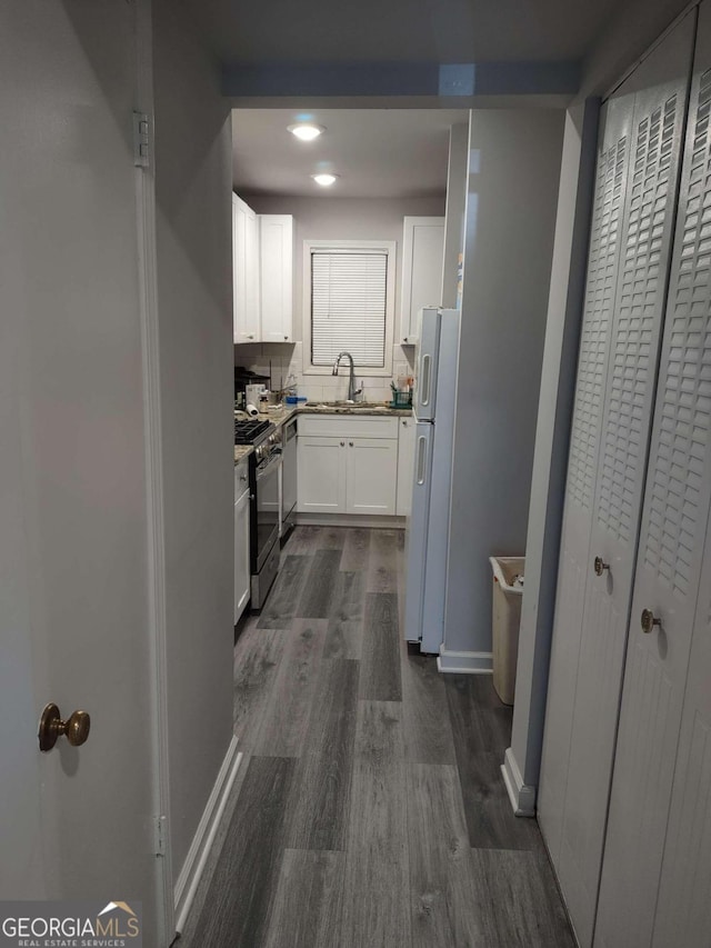 kitchen featuring dark wood-type flooring, sink, white cabinets, decorative backsplash, and stainless steel appliances