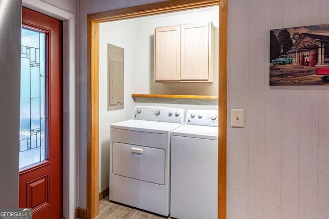 clothes washing area featuring light wood-type flooring, washing machine and clothes dryer, cabinet space, and electric panel