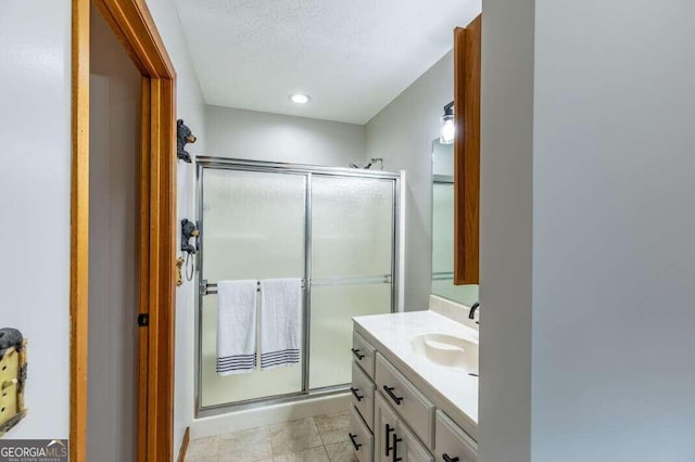 full bath featuring a stall shower, a textured ceiling, and vanity