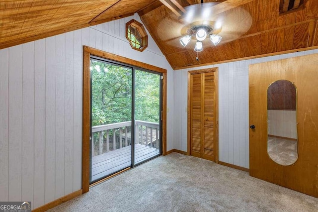 unfurnished bedroom with lofted ceiling, carpet, access to outside, wood walls, and a closet