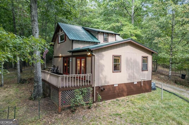 view of property exterior with french doors, a yard, crawl space, metal roof, and a view of trees