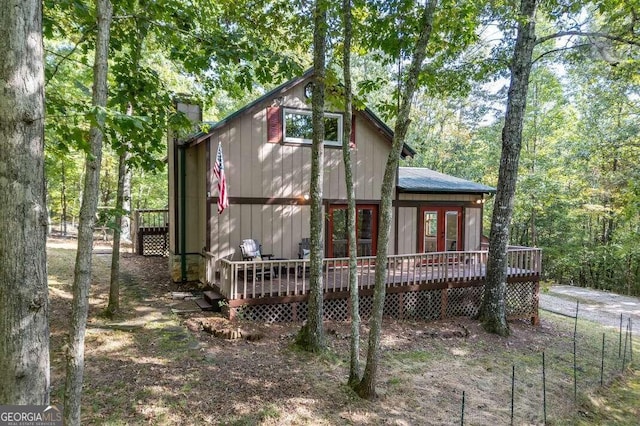 back of house with a wooden deck, a chimney, and french doors