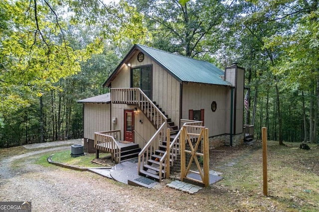 view of outbuilding featuring stairway, a wooded view, and central AC unit