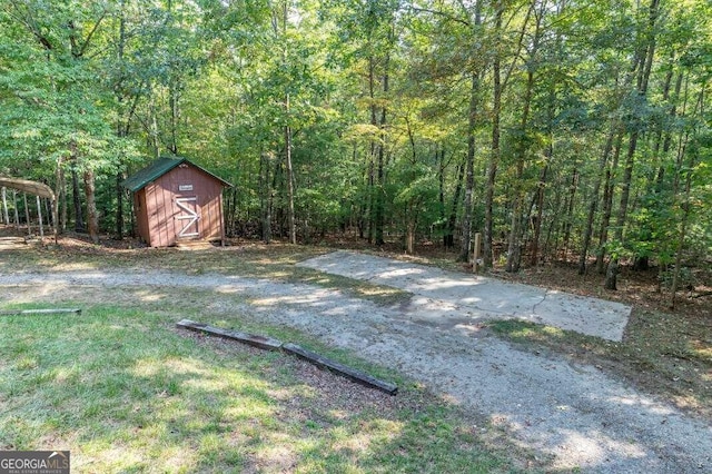 view of yard with a shed, a view of trees, and an outdoor structure