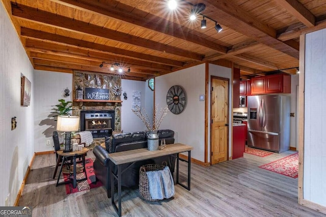 dining space featuring a stone fireplace, beamed ceiling, and light wood-type flooring