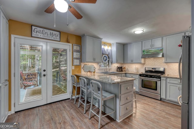 kitchen featuring light wood-type flooring, sink, kitchen peninsula, appliances with stainless steel finishes, and ceiling fan