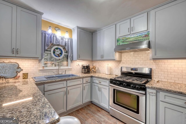 kitchen featuring stainless steel range with gas cooktop, premium range hood, light hardwood / wood-style flooring, and light stone counters