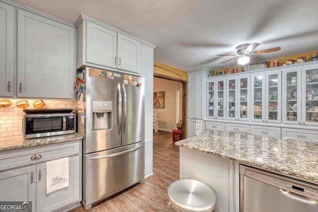 kitchen featuring ceiling fan, light hardwood / wood-style flooring, backsplash, white cabinetry, and appliances with stainless steel finishes