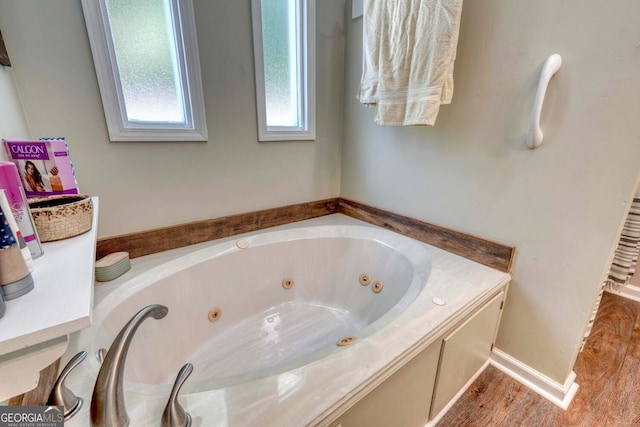 bathroom with wood-type flooring and a tub to relax in