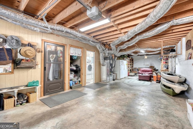 basement featuring white refrigerator and washer / dryer