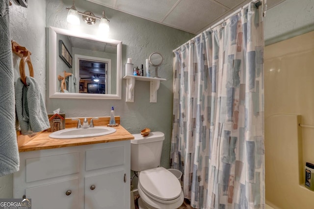 bathroom with curtained shower, a paneled ceiling, vanity, and toilet