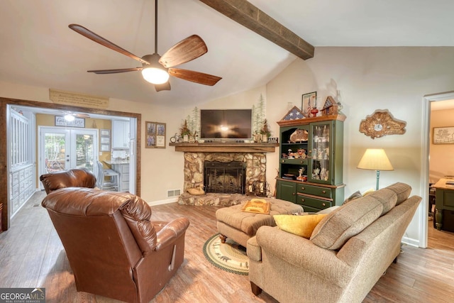 living room with a stone fireplace, lofted ceiling with beams, hardwood / wood-style floors, and ceiling fan