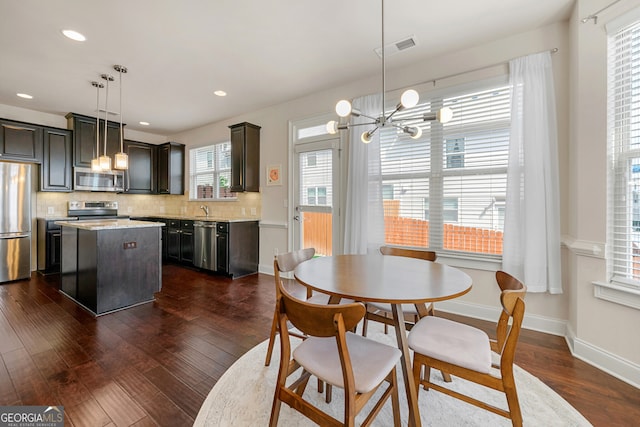 dining room with dark hardwood / wood-style floors, an inviting chandelier, and plenty of natural light