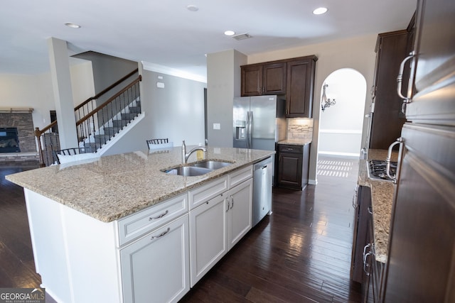 kitchen with a stone fireplace, a kitchen island with sink, appliances with stainless steel finishes, sink, and white cabinetry