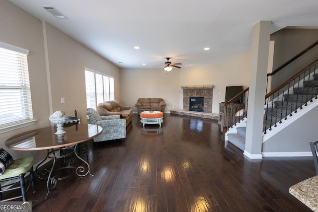 living room featuring ceiling fan, dark hardwood / wood-style floors, and a fireplace