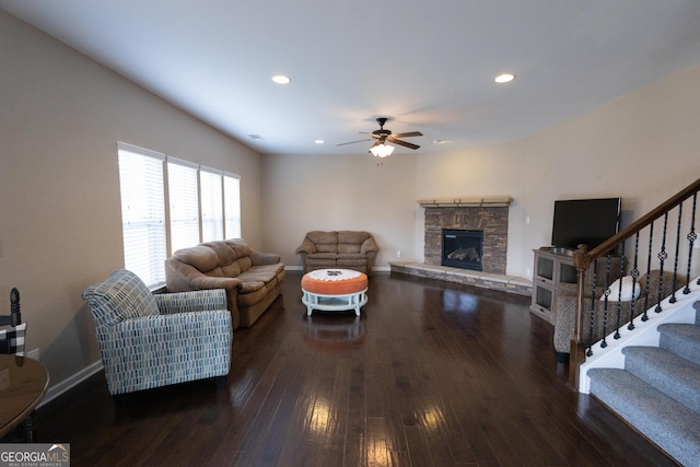 living room with dark hardwood / wood-style floors, ceiling fan, and a stone fireplace