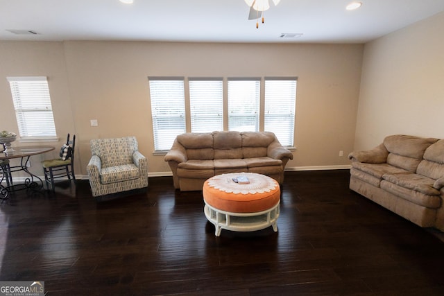 living room with dark wood-type flooring, ceiling fan, and a wealth of natural light