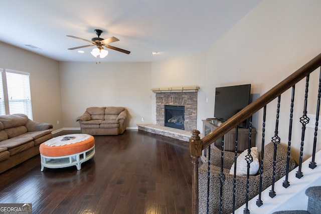 living room with wood-type flooring, ceiling fan, and a stone fireplace