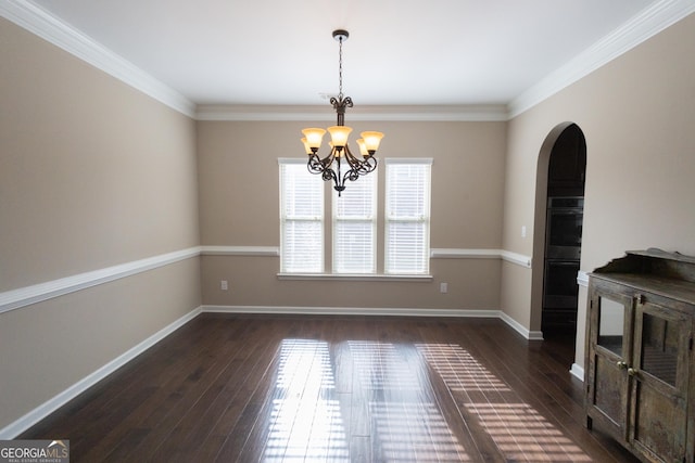 unfurnished dining area featuring dark wood-type flooring, a notable chandelier, and crown molding