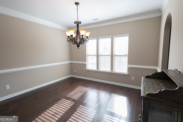 unfurnished dining area featuring dark hardwood / wood-style flooring, an inviting chandelier, and crown molding