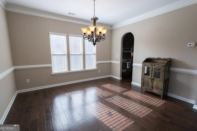 empty room featuring ornamental molding, dark hardwood / wood-style flooring, and a chandelier