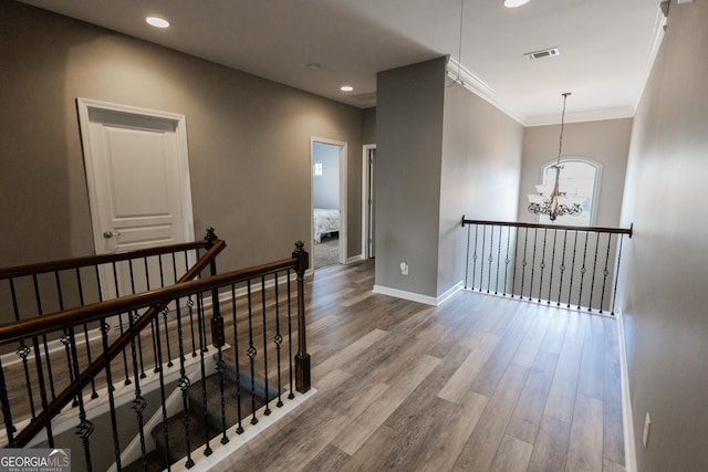 corridor with wood-type flooring, an inviting chandelier, and ornamental molding