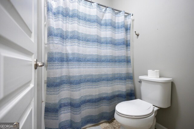 bathroom with toilet and a shower with shower curtain