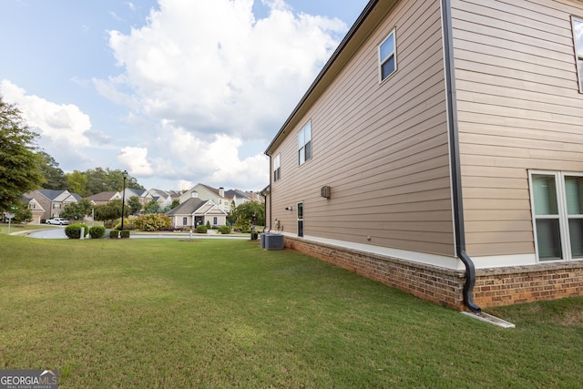 view of side of property with central air condition unit and a yard