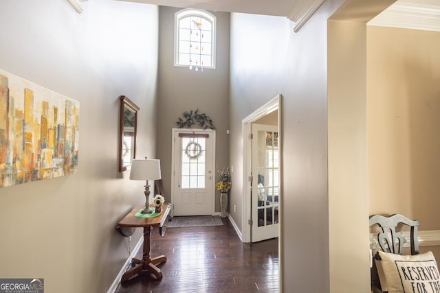 entryway with a high ceiling, dark hardwood / wood-style flooring, a wealth of natural light, and crown molding