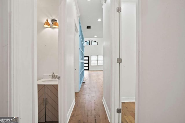 hallway with sink and light hardwood / wood-style flooring